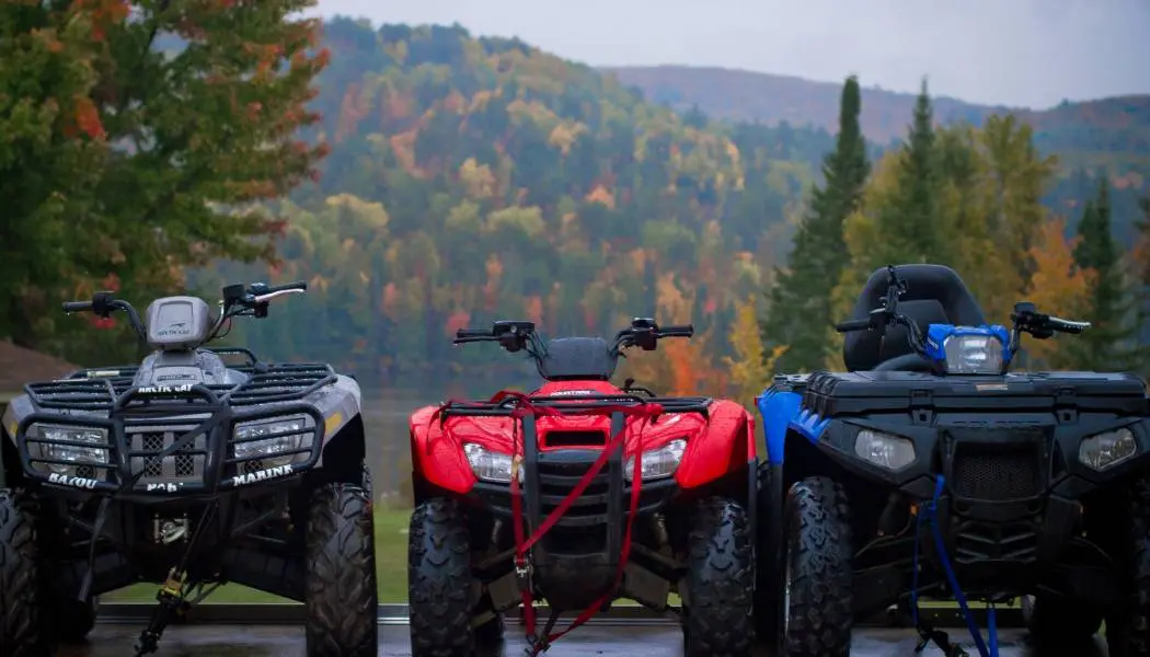Three ATVs are lined up on a trailer ready for a guided tour or rental in Northeastern Ontario.