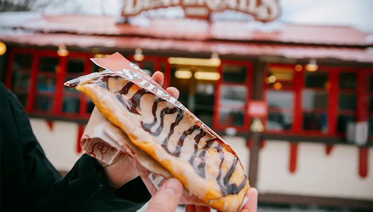 Une personne tenant une queue de castor devant un kiosque BeaverTails.