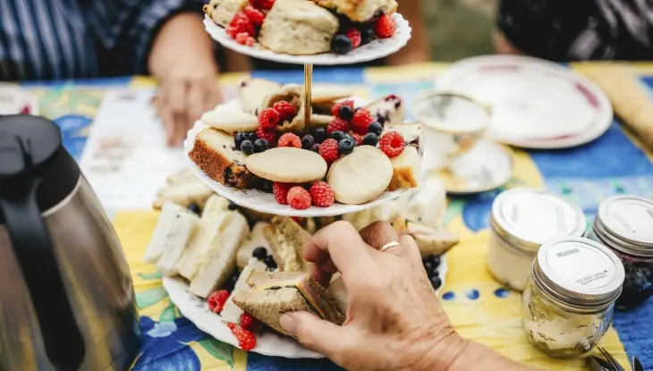 Une main tendue vers un sandwich sur un présentoir à trois niveaux à la ferme fruitière Berrylicious.
