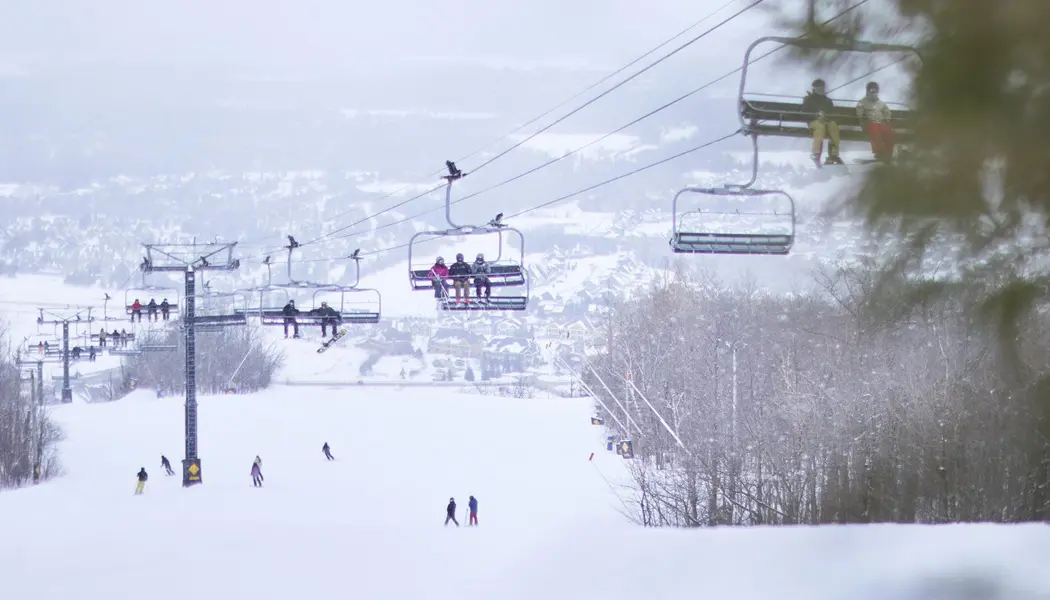 Les skieurs et les planchistes remontent en télésiège jusqu'au sommet de la piste de ski enneigée de Blue Mountain.