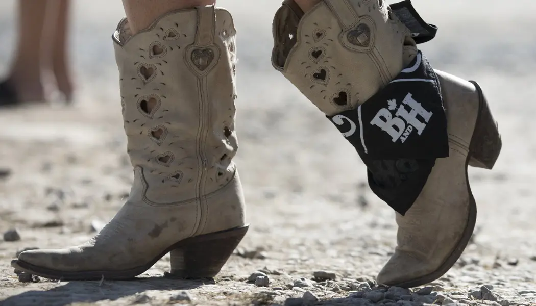 Primer plano de un par de botas de vaquero de mujer decoradas con corazones y un pañuelo.