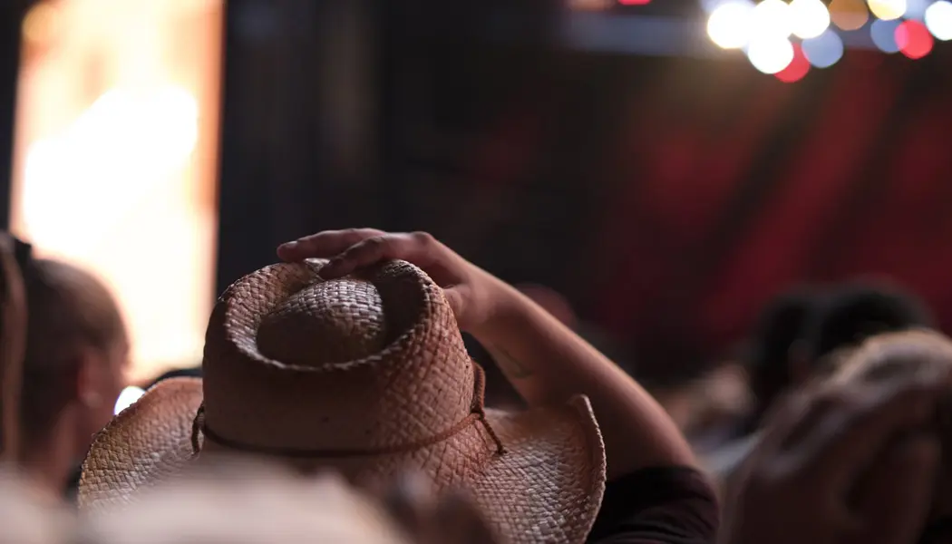 Eine Person richtet ihren Cowboyhut aus Stroh in einem dicht gedrängten Publikum beim Country-Musikfestival „Boots and Hearts“.