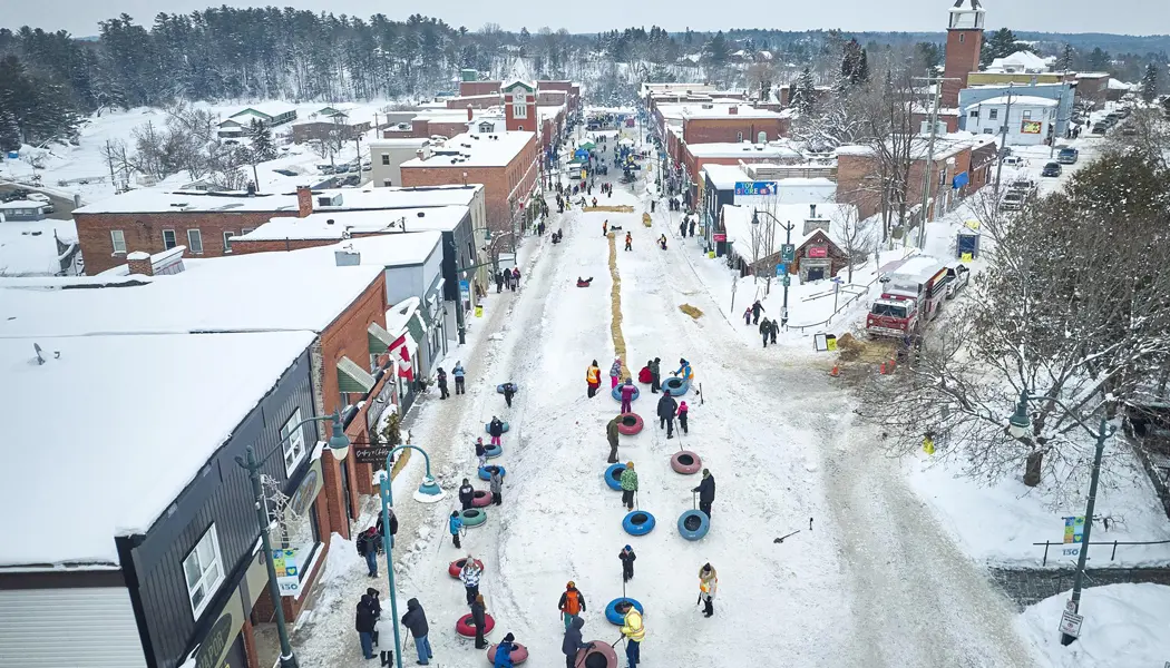 View of Main Street in Bracebridge filled with people snow tubing and celebrating during the annual winter Fire and Ice festival.