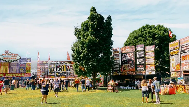Foules circulant parmi des kiosques alimentaires et de barbecue en plein air durant le Ribfest à Brockville.