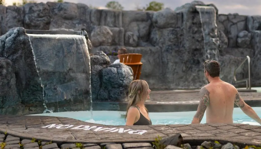 Un couple se tient dans une piscine extérieure chauffée du Cedar Meadows Nordic Spa à Timmins.