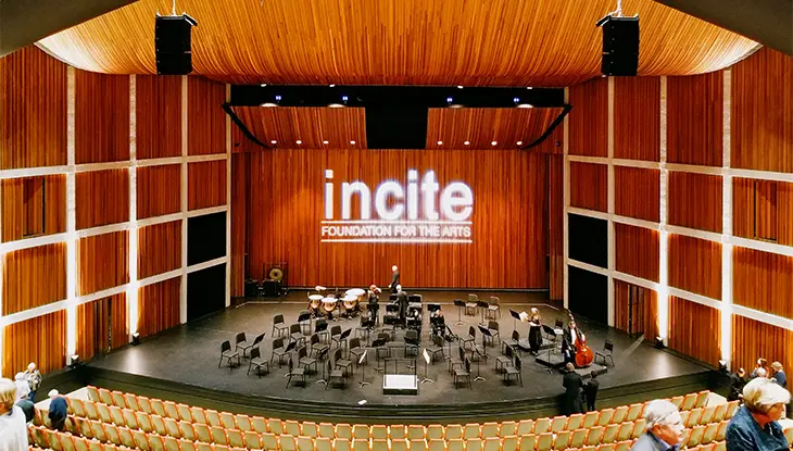Vue large de la scène d’une salle de concert moderne, préparée pour une performance symphonique.