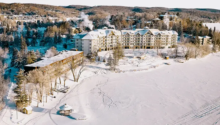 Eine Luftaufnahme des Deerhurst Resort mit einem schneebedeckten See und Gelände.