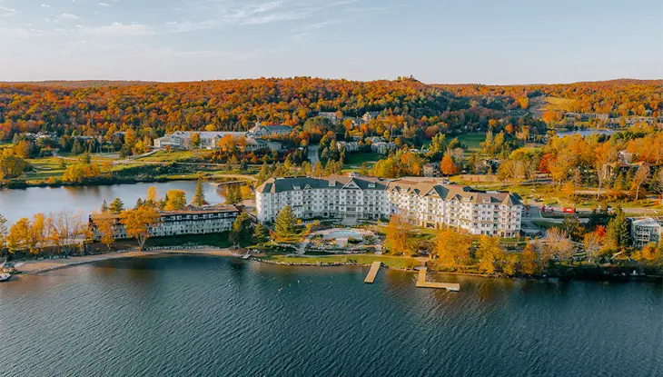Aerial view of Deerhurst Resort overlooking a deep blue lake surrounded by fall colour.