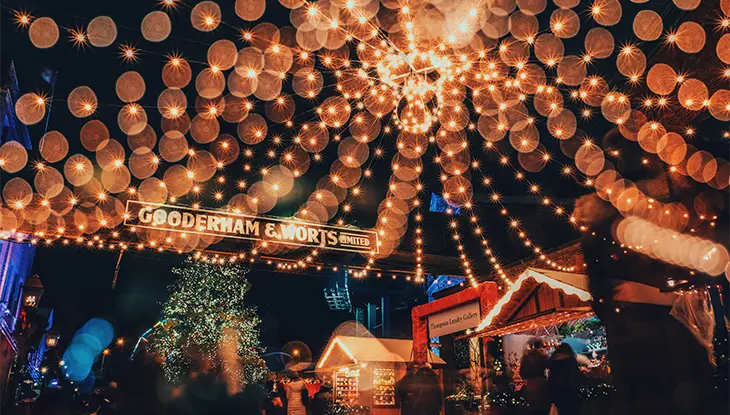 Installation de lumières s’étendant au-dessus du marché et éclairant le ciel nocturne et tous les marchands des Fêtes.