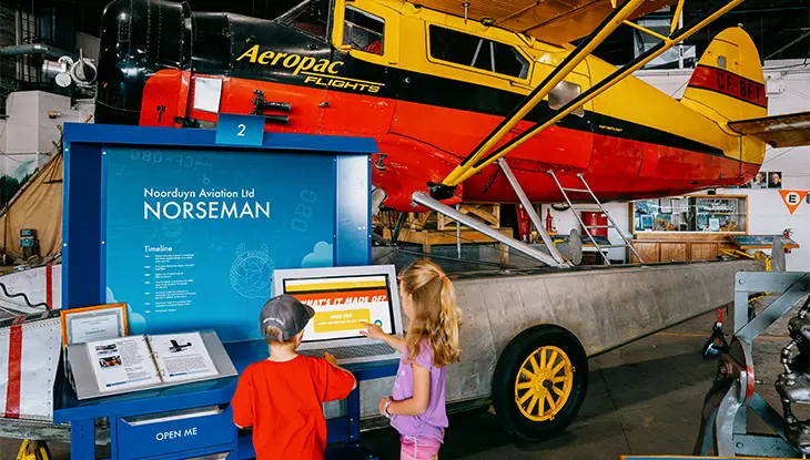 Historic aircraft displayed inside an aviation museum with interactive exhibits and visitors.