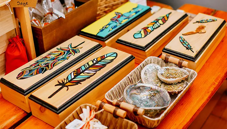 Ausstellung von handgefertigtem Schmuck und Dekorationsartikeln der First Nations auf einem hölzernen Verkaufstisch.