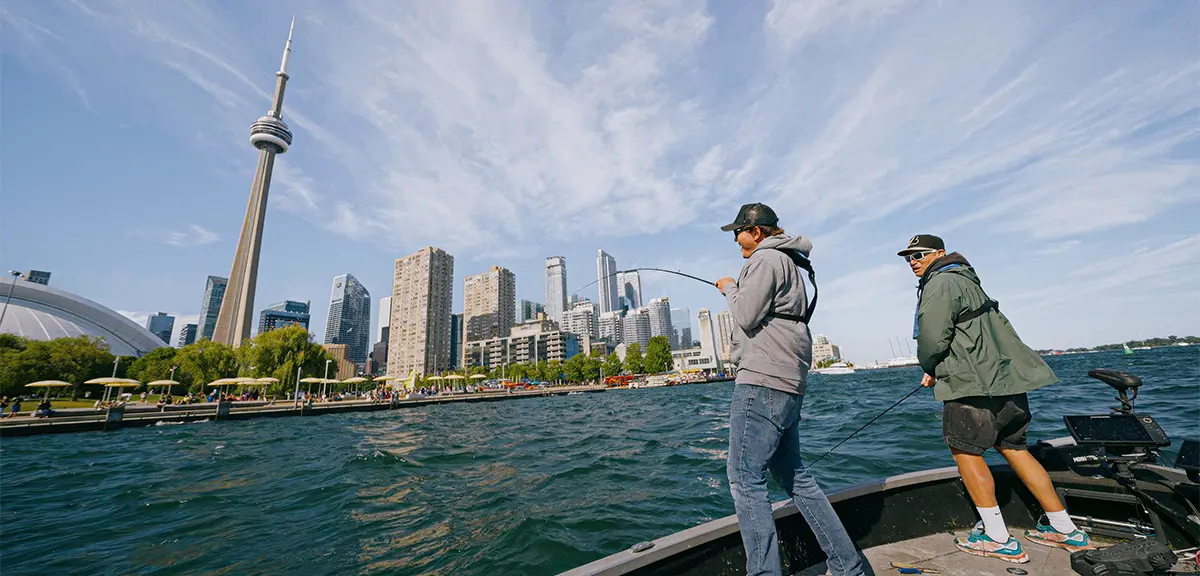 Deux pêcheurs à la ligne taquinent le poisson depuis le côté d'un bateau dans le port de Toronto.