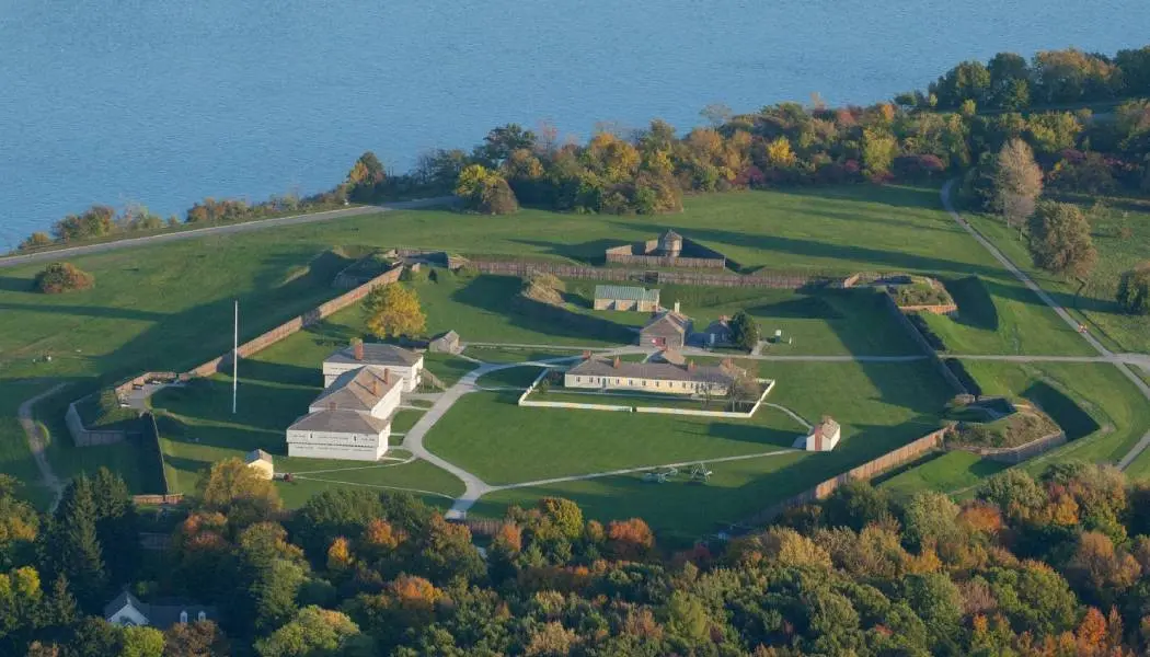 Aerial view of a manicured lawn and several buildings next to the Niagara River at Fort George National Historic Site.