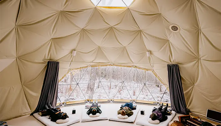 Interior de un espacio en forma de cúpula con techo de tela y asientos en el suelo.