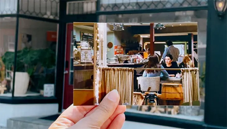 Eine Hand hält ein Foto eines Restaurants vor dem Restaurant hoch, in dem eine Szene aus der Serie Gilmore Girls gedreht wurde.