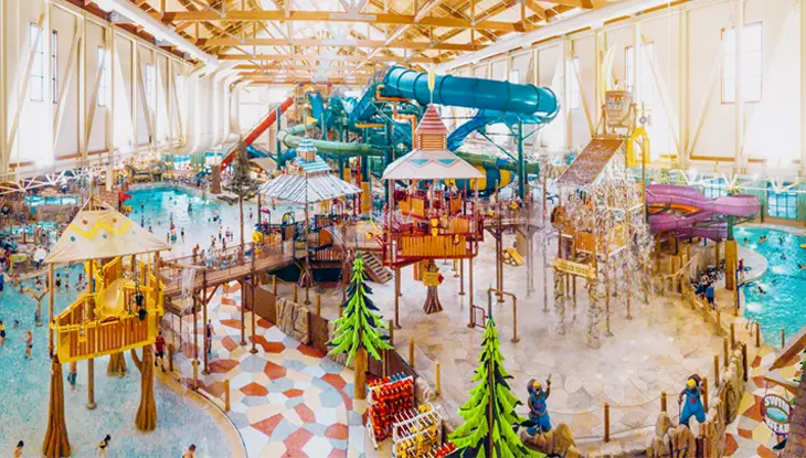 Un colorido parque acuático cubierto con zona de chapoteo, área de piscina y toboganes de agua.