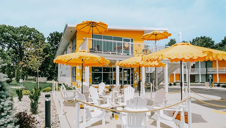 Chaises Muskoka blanches et parasols orange composant une aire de détente extérieure au Grove Motel.