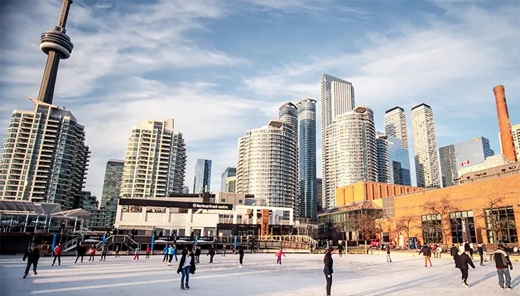 Skating on a waterfront ice rink with Toronto's cityscape in the background.