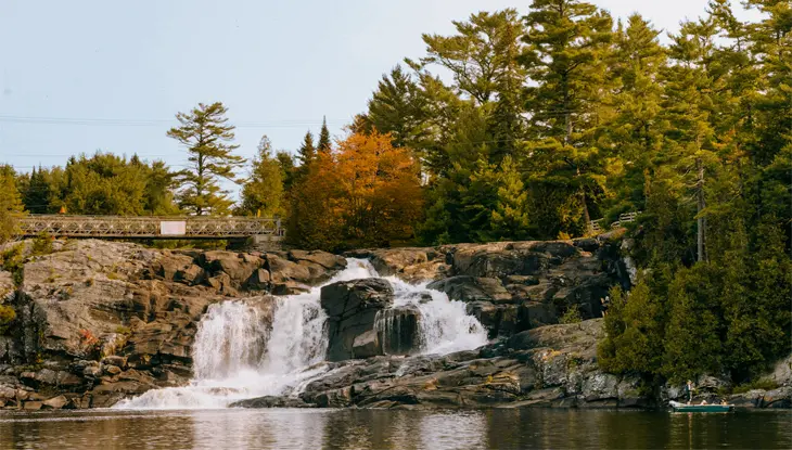 Water cascades in two streams down a rock face below a foot bridge at High Falls in Bracebridge.