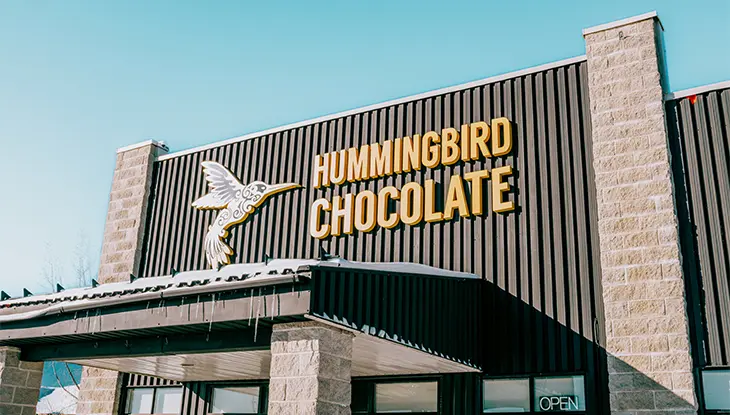 Außenansicht des Gebäudes von Hummingbird Chocolate mit Beschilderung und modernem Industriedesign.