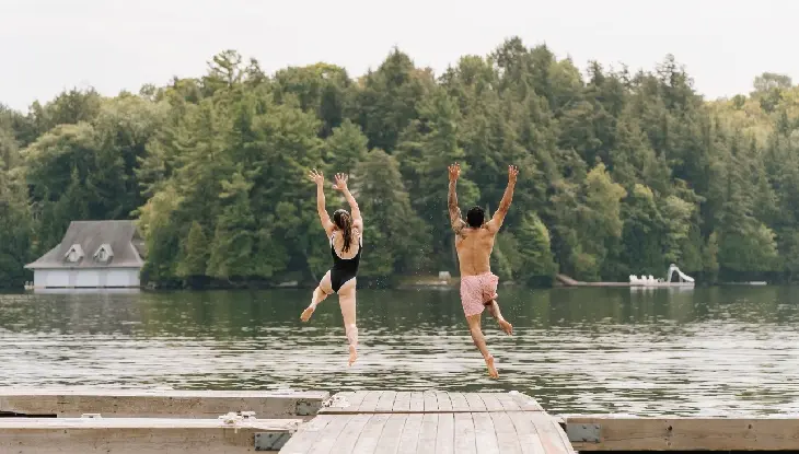 Un homme et une femme sautant dans le lac près du JW Marriott The Rosseau Muskoka Resort & Spa..