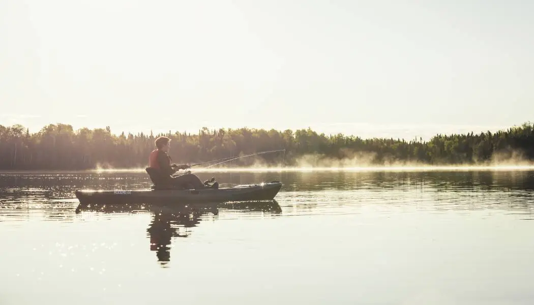 Pêcheur en kayak ayant mis sa ligne à l’eau sur un majestueux lac du Nord-Ouest de l’Ontario.