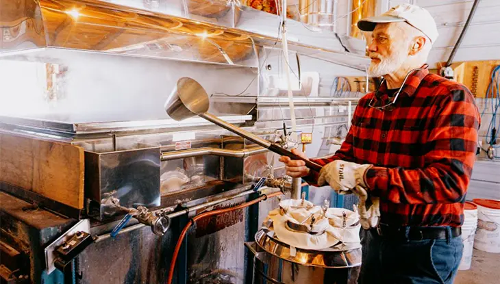 Producer tending maple syrup equipment inside a sugar shack.