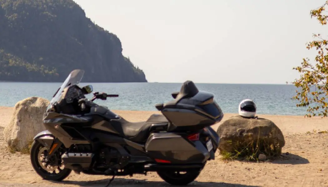 Une moto de tourisme est garée sur la plage sablonneuse à la baie Old Woman, avec une vue sur les eaux bleues du lac Supérieur.