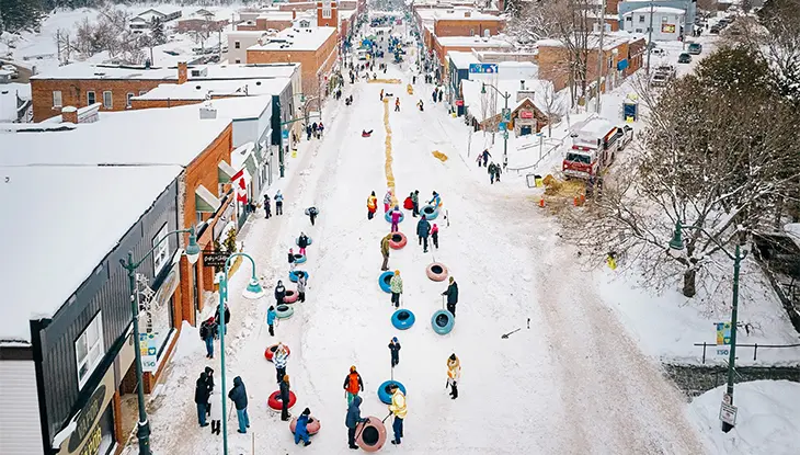 Vue de la rue principale de Bracebridge remplie de gens qui font de la luge sur neige et célèbrent le festival annuel d'hiver Feu et Glace.