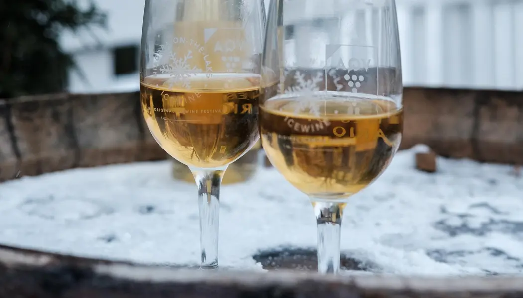 Deux verres de vin reposent sur un tonneau à vin en bois recouvert de neige, à l'extérieur, lors du festival annuel du vin de glace de Niagara.