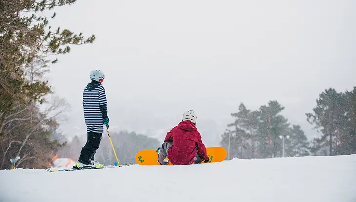 Two snowboarders rest at the top of a snowy hill at Laurentian Ski Park in North Bay.