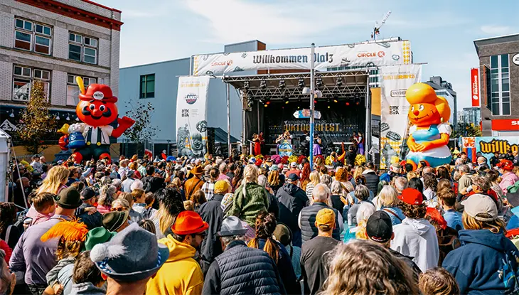Foule nombreuse réunie devant la scène en plein air d’un festival, sur une place du centre-ville.