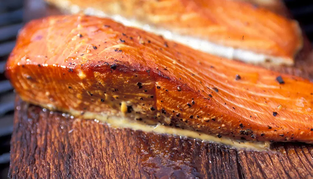 Un steak de poisson tendre et délicieux, fraîchement cuit à la flamme et servi sur une planche de bois rustique.