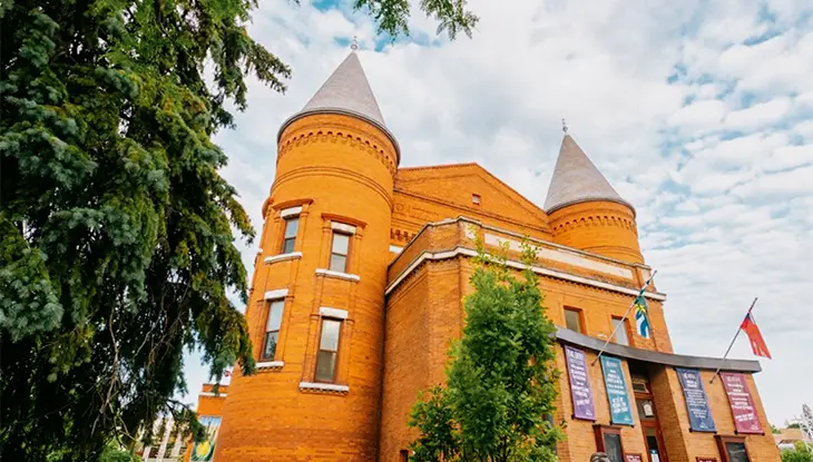Historic red brick building with turrets and banners at the entrance.