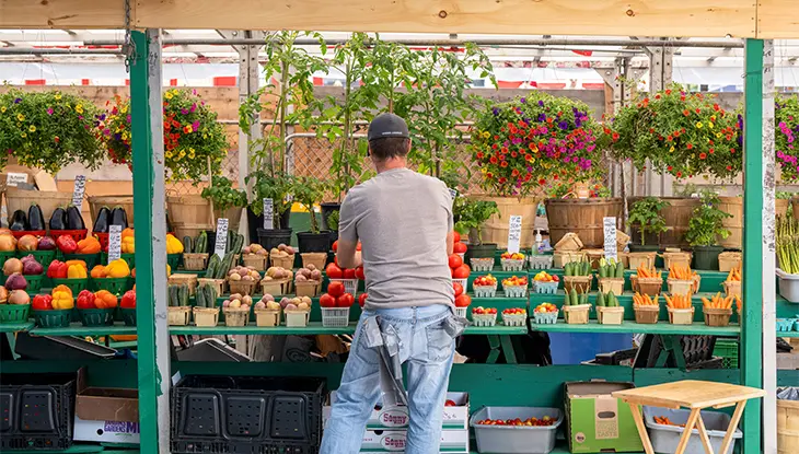 Ein Verkäufer arrangiert frisches Gemüse und andere Produkte an einem Marktstand im Freien auf dem ByWard Market in Ottawa.