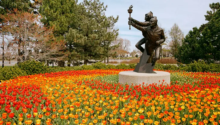 Bronzestatue, umgeben von blühenden roten und gelben Tulpen im Major’s Hill Park in Ottawa.