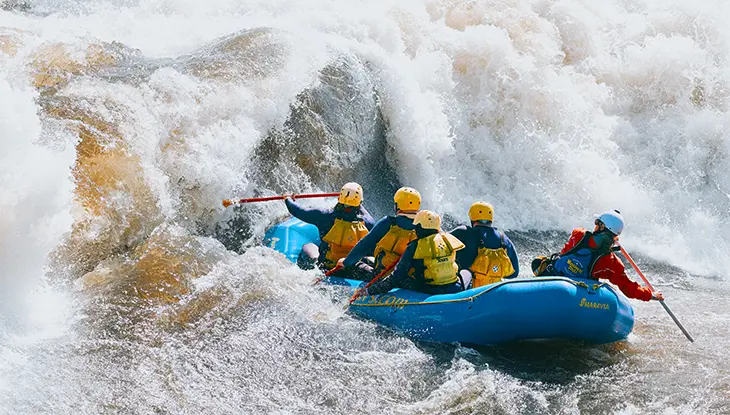 A group of paddlers brave a massive wave while whitewater rafting on the Ottawa River.
