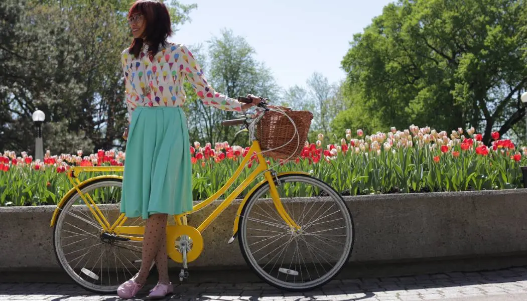Una mujer posa con una bicicleta amarilla junto a un macizo de coloridos tulipanes durante el festival de los tulipanes en Ottawa.