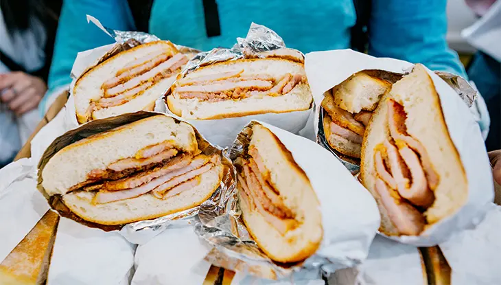 Sandwichs au bacon enrobé de semoule de maïs tranchés, emballés dans du papier et empilés les uns sur les autres.