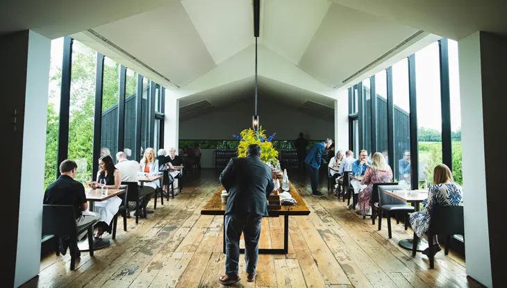 Des visiteurs assis à des tables au bord de fenêtres allant du sol au plafond au restaurant Pearl Morissette, étoilé par le Guide MICHELIN.