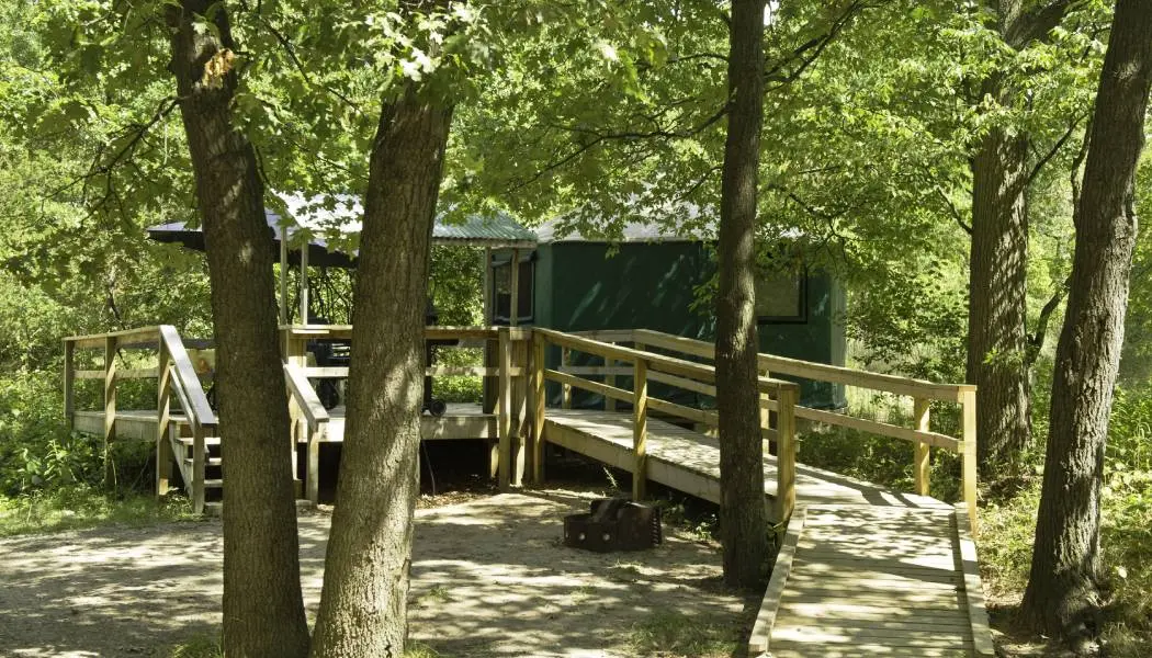 Im Pinery Park in Ontario umgeben hohe Bäume eine Jurte mit barrierefreier Rampe und Holzterrasse.