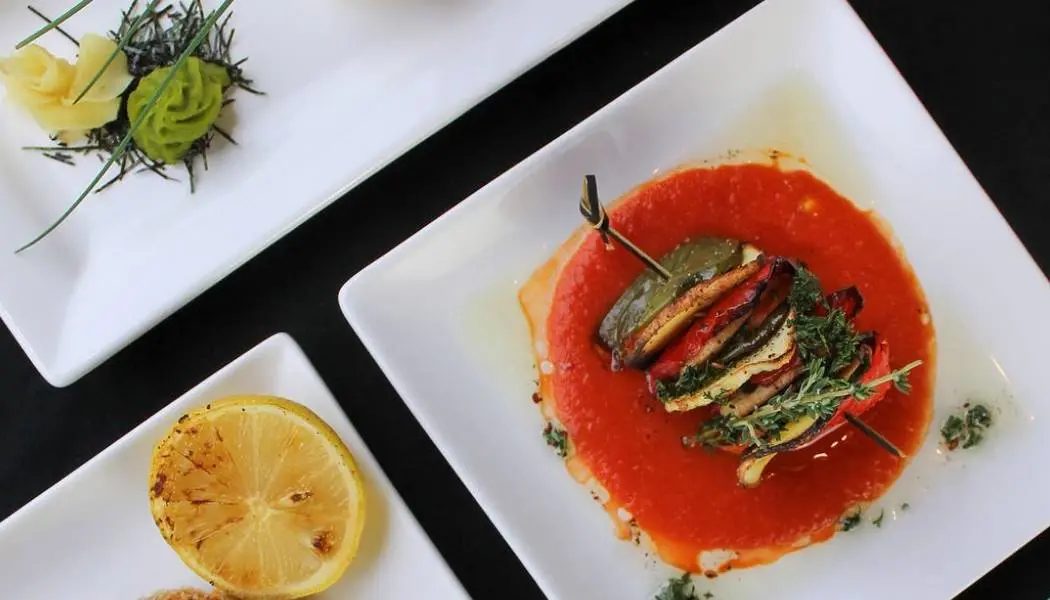 Une assiette de légumes rôtis en brochettes sur un fond de sauce tomate, servie dans un restaurant végétarien de London, en Ontario.