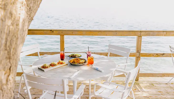 Auf der Terrasse des Lakeside Motels in Prince Edward County wurde im Freien ein Tisch mit Speisen und Getränken gedeckt.