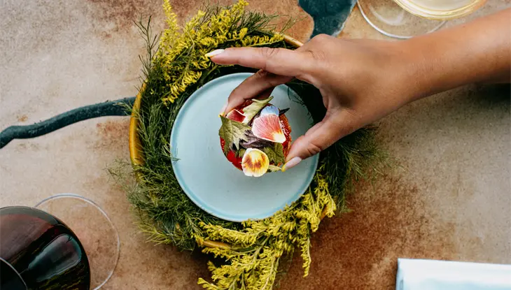 A person lifts a colourful bite-sized savoury snack from a plate at the Restaurant at Pearl Morissette.