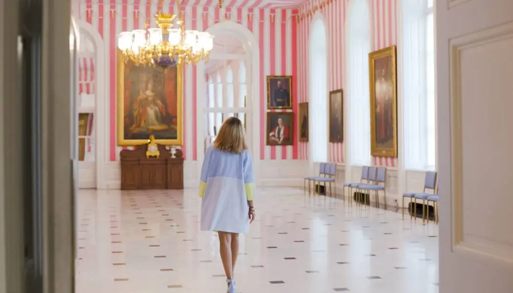Une dame entre dans la salle aux murs recouverts d’un papier peint à rayures roses et blanches à l’occasion d’une visite spéciale de Rideau Hall à Ottawa.