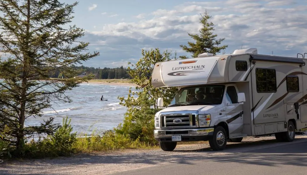 Ein Wohnmobil steht neben einem Sandstrand am Lake Superior, wo eine Person schwimmt.