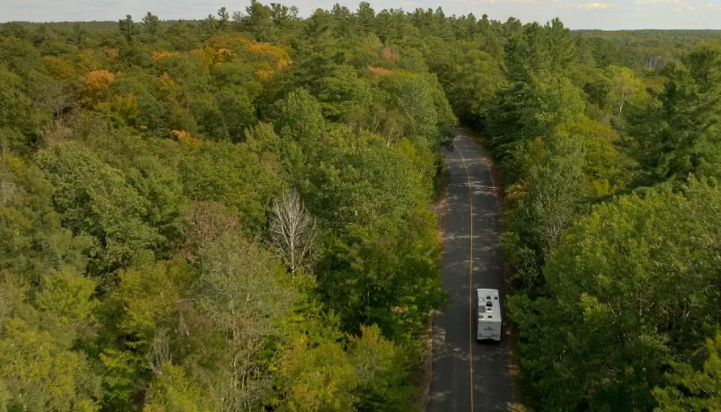 Luftaufnahme eines Wohnmobils, das auf einer bewaldeten Nebenstraße in den Haliburton Highlands fährt.