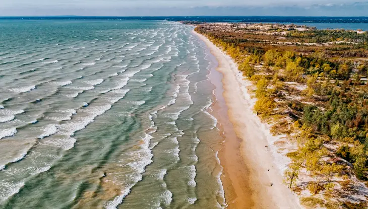 Luftaufnahme der sandigen Küstenlinie und der rollenden Wellen im Sandbanks Provincial Park.
