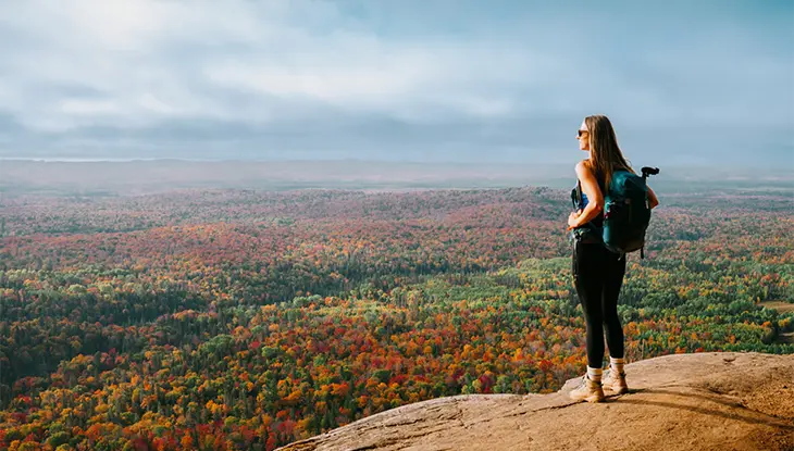 Randonneur se tenant à un point de vue panoramique surplombant la forêt d’automne aux falaises Robertson, près de Sault Ste. Marie.