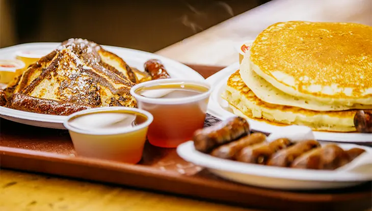 Breakfast plate with pancakes, French toast, sausages, and maple syrup served at Shaw’s Maple Syrup.